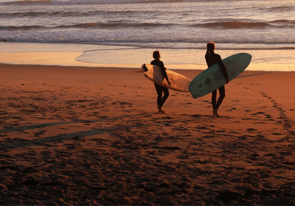 Two people on beach ready to surf
