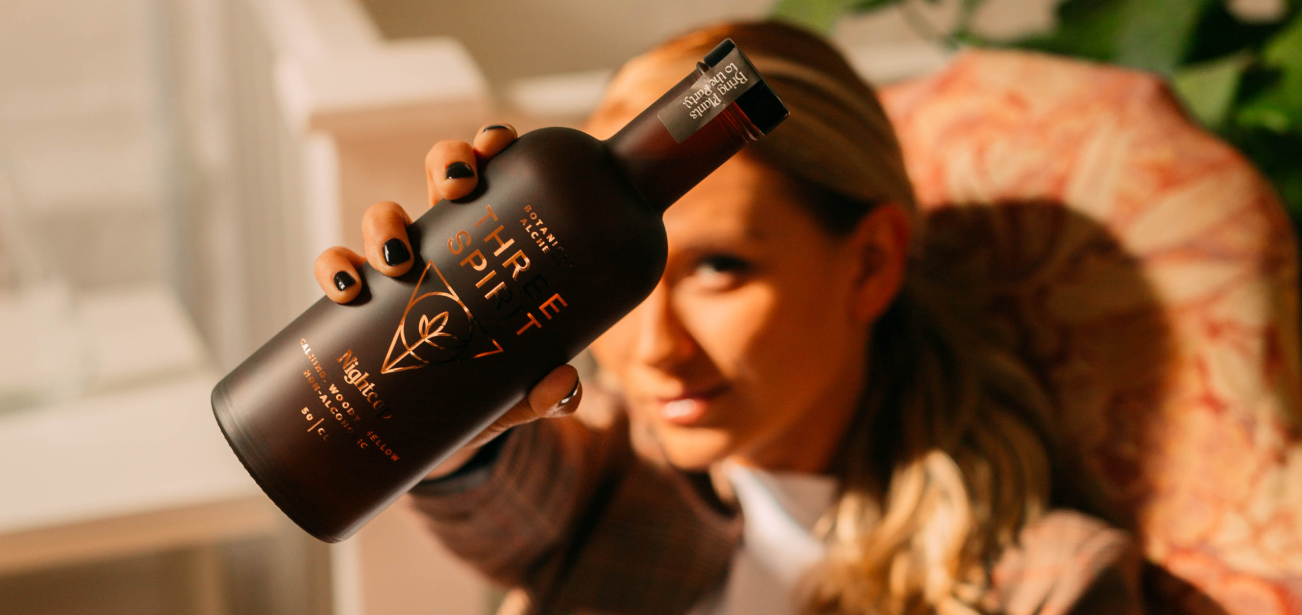 Woman holding bottle of Three Spirits drink